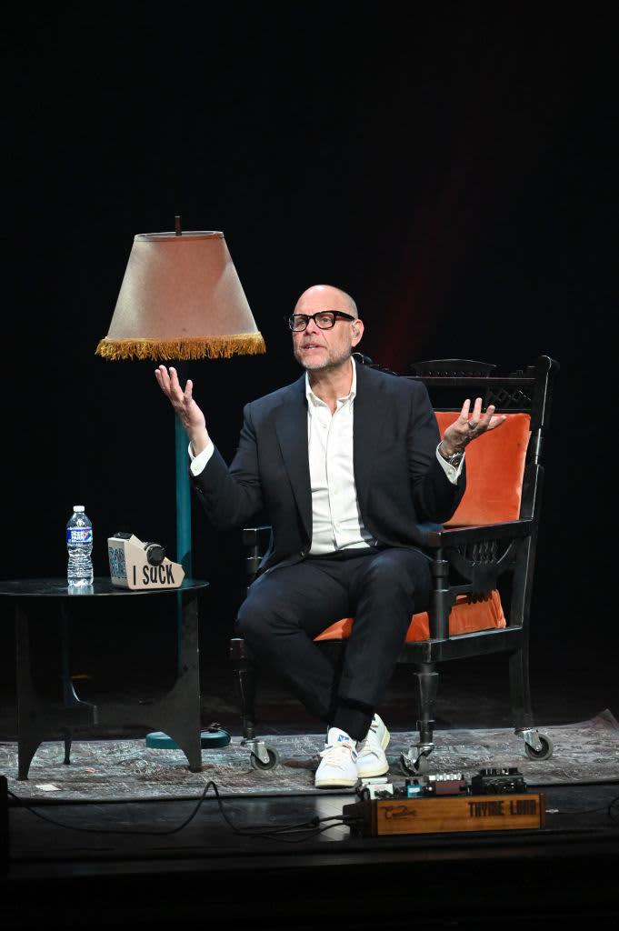Alton Brown sitting in a chair speaking
