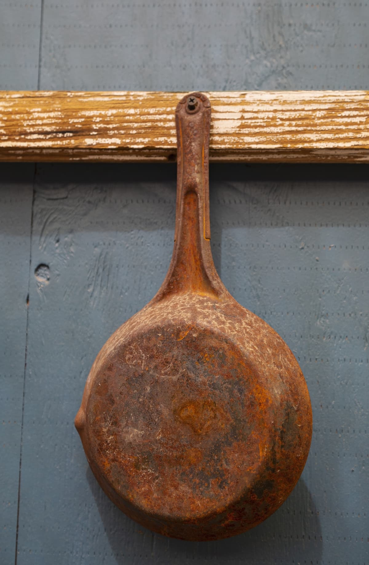 A rusty pan hanging on the wall