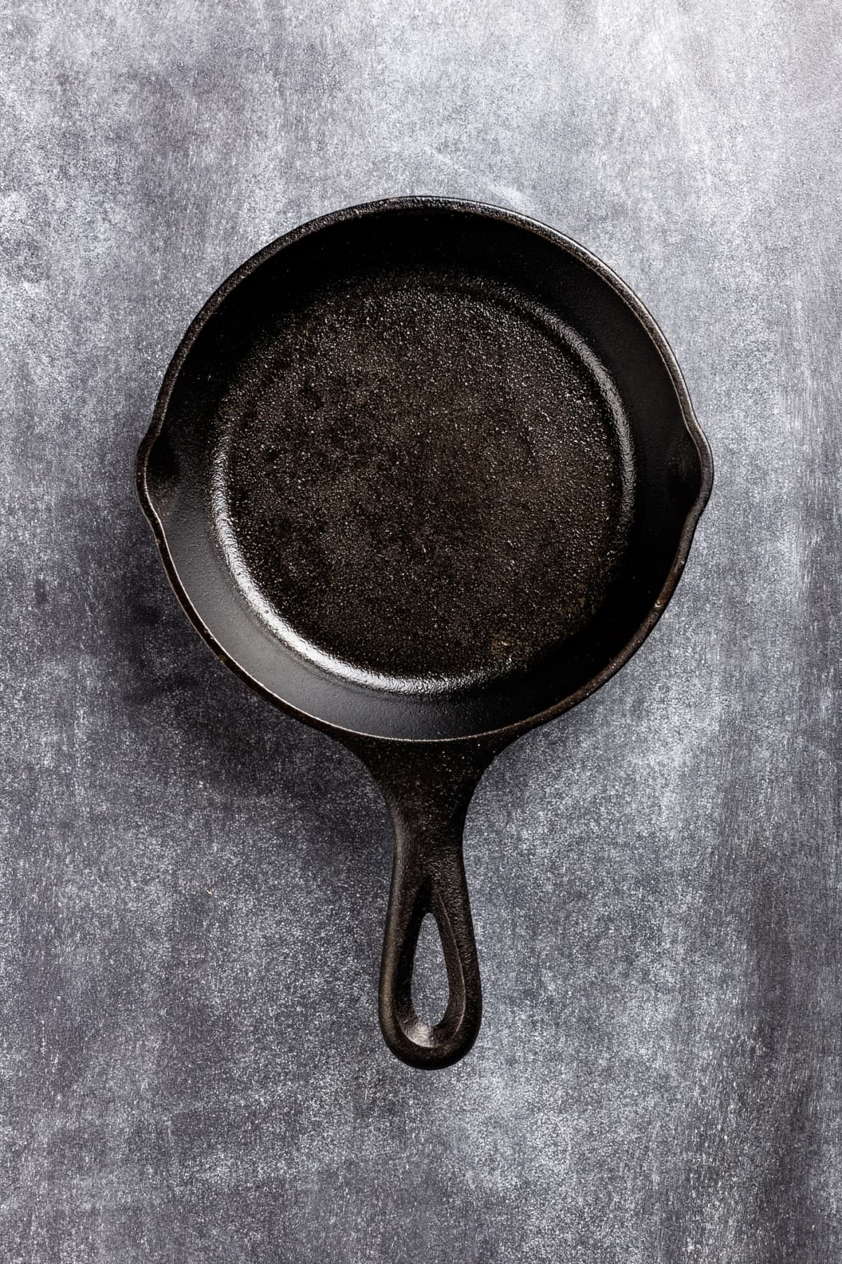 Old rusted cast iron frying pan hanging on wall