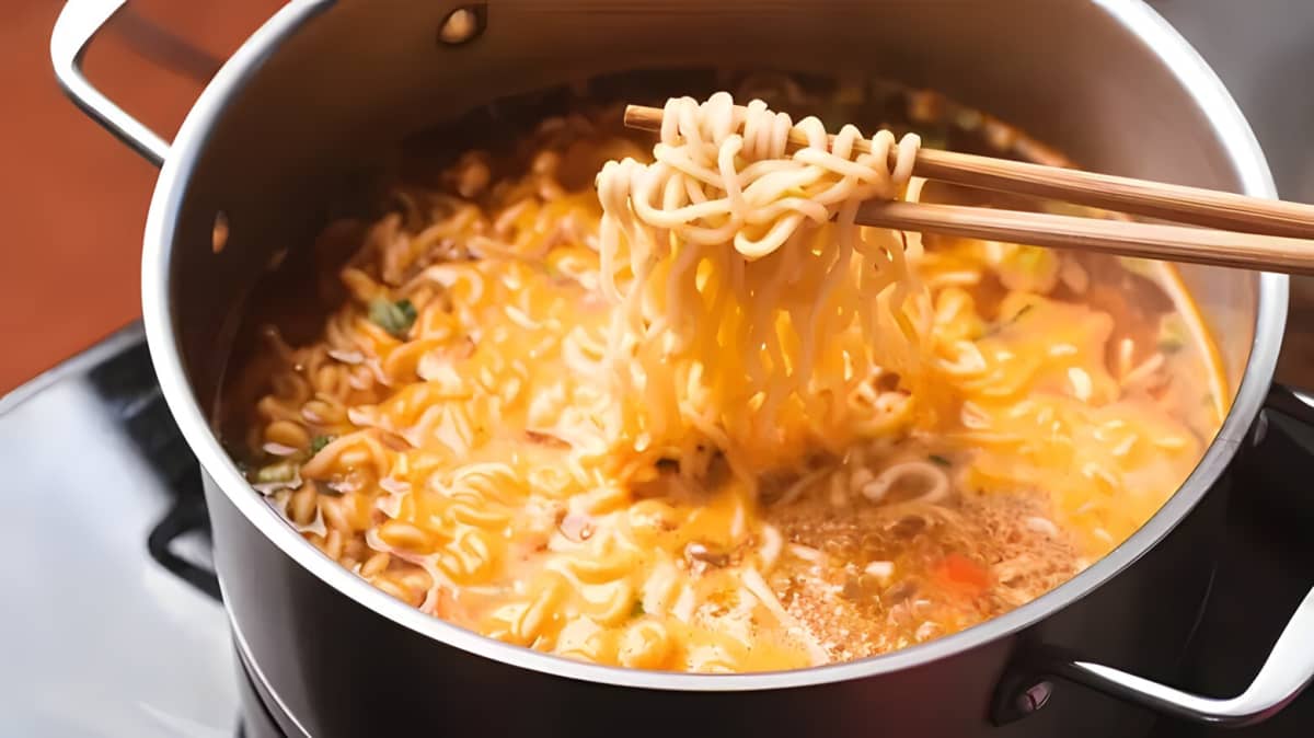 Chopsticks grabbing noodles from a pot of ramen