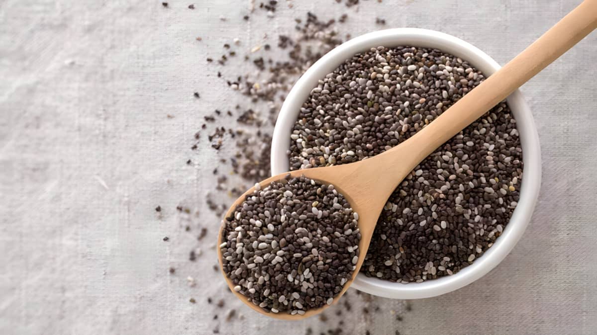Spoon of chia seeds on top of bowl of chia seeds