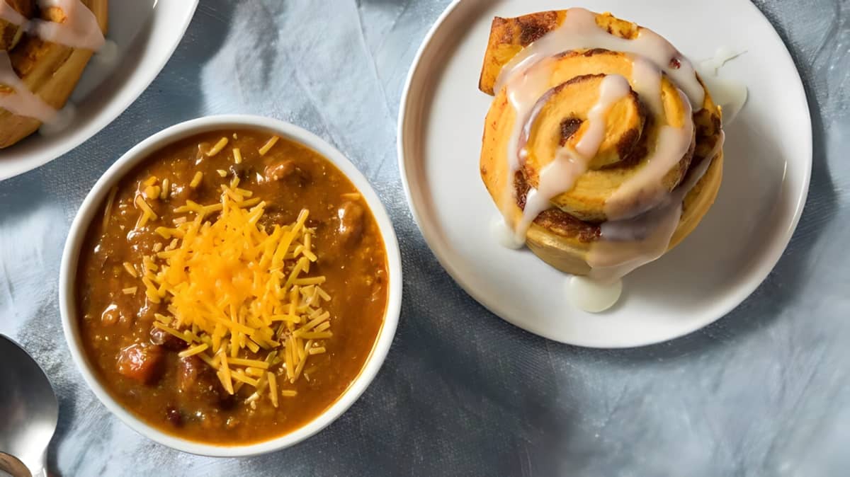 Bowls of chili and cinnamon roll.