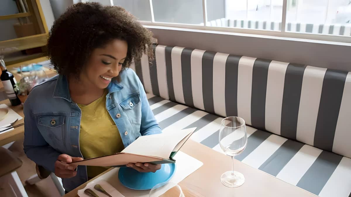 A woman looks at a menu in a restaurant.