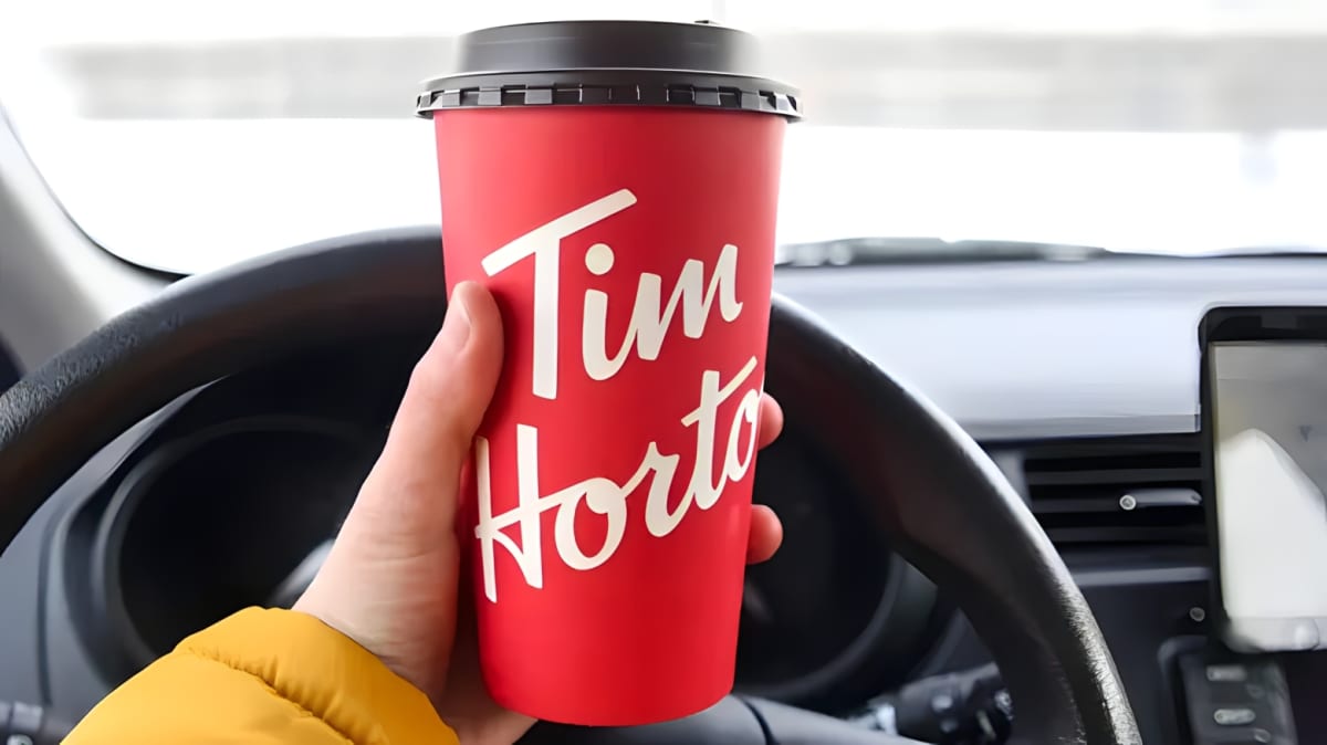 A person holds a Tim Horton's coffee in their car.