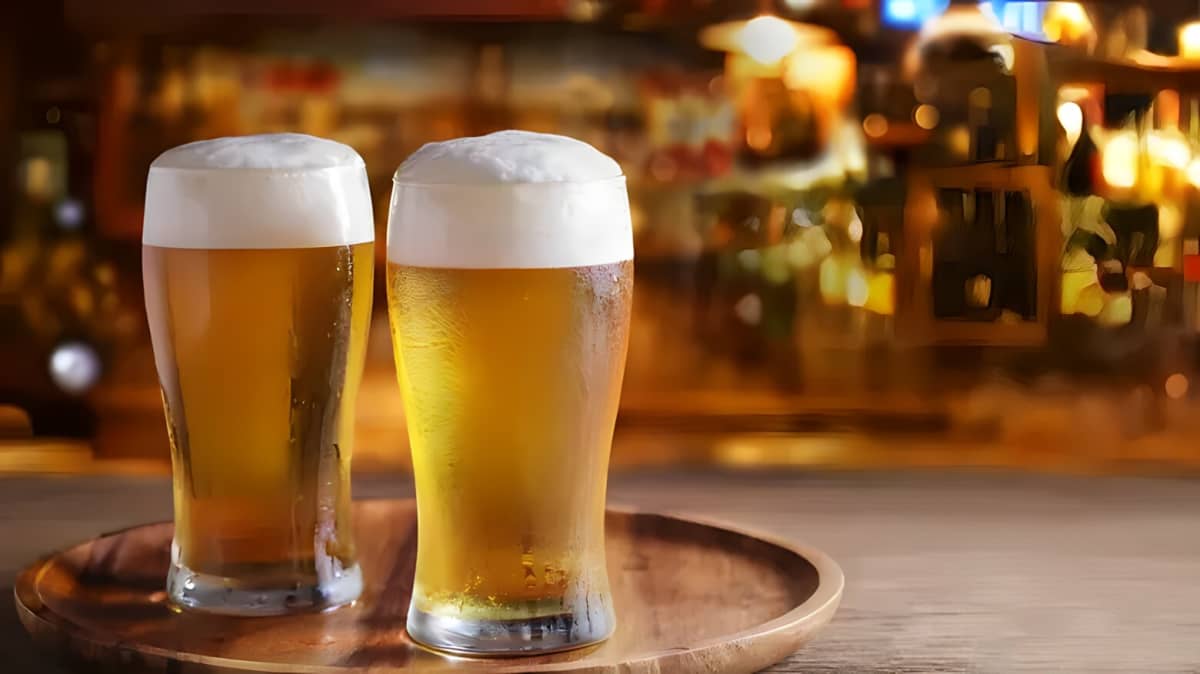 Two glasses of beer on a bar.