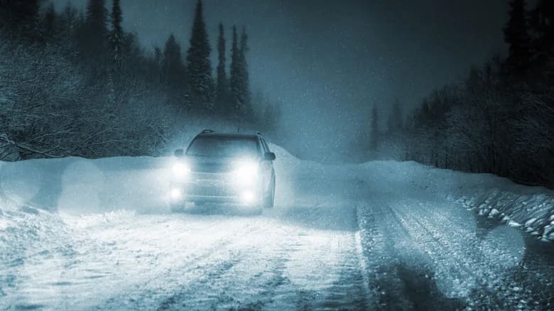 Car driving in snow at night