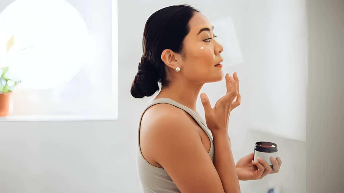 Woman applying product to her face.