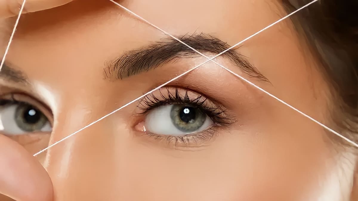 Close up of a woman threading her eyebrows.