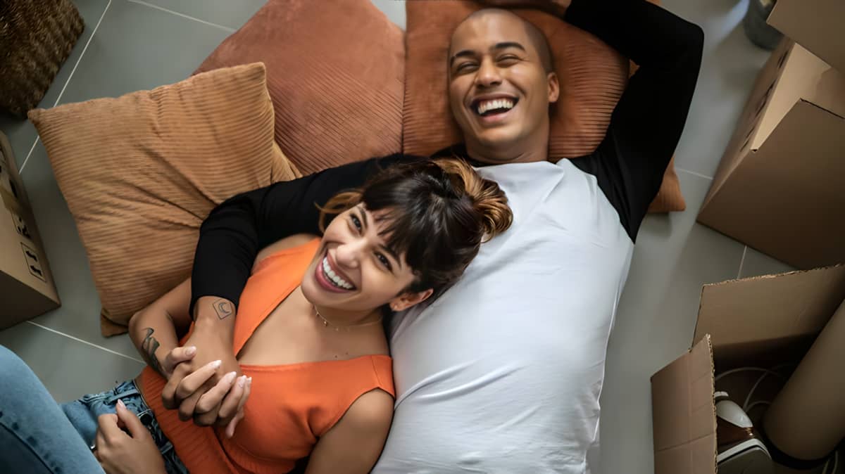 Man and woman cuddling and laughing together on a couch.