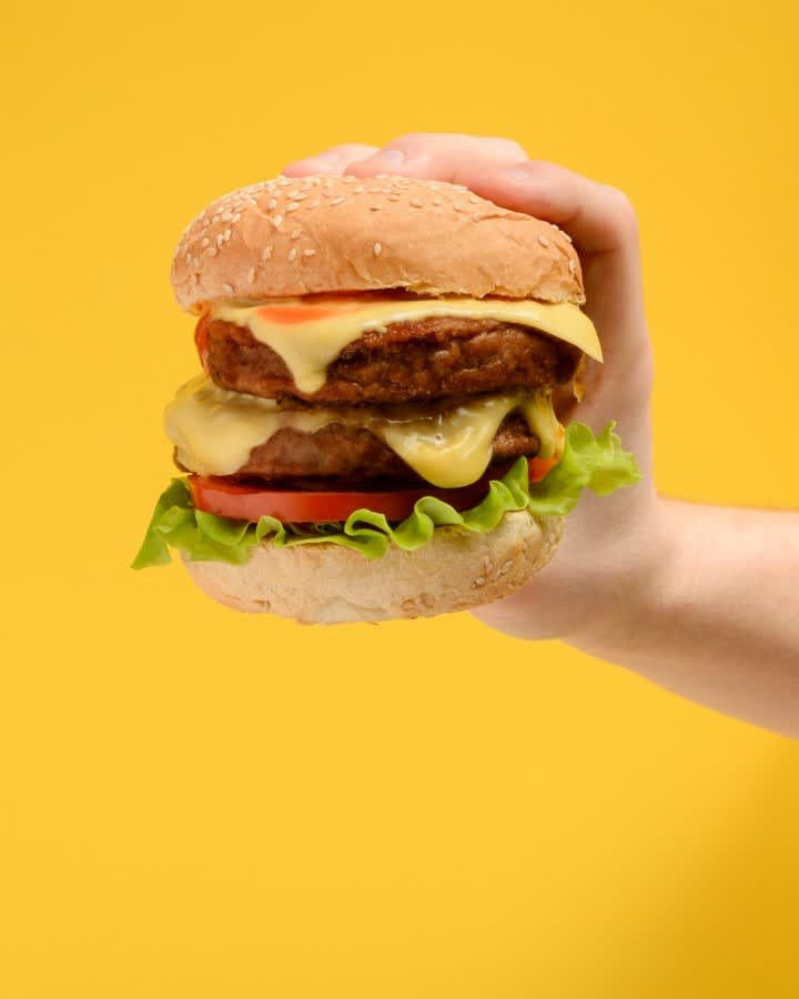 Hand holding a cheeseburger.