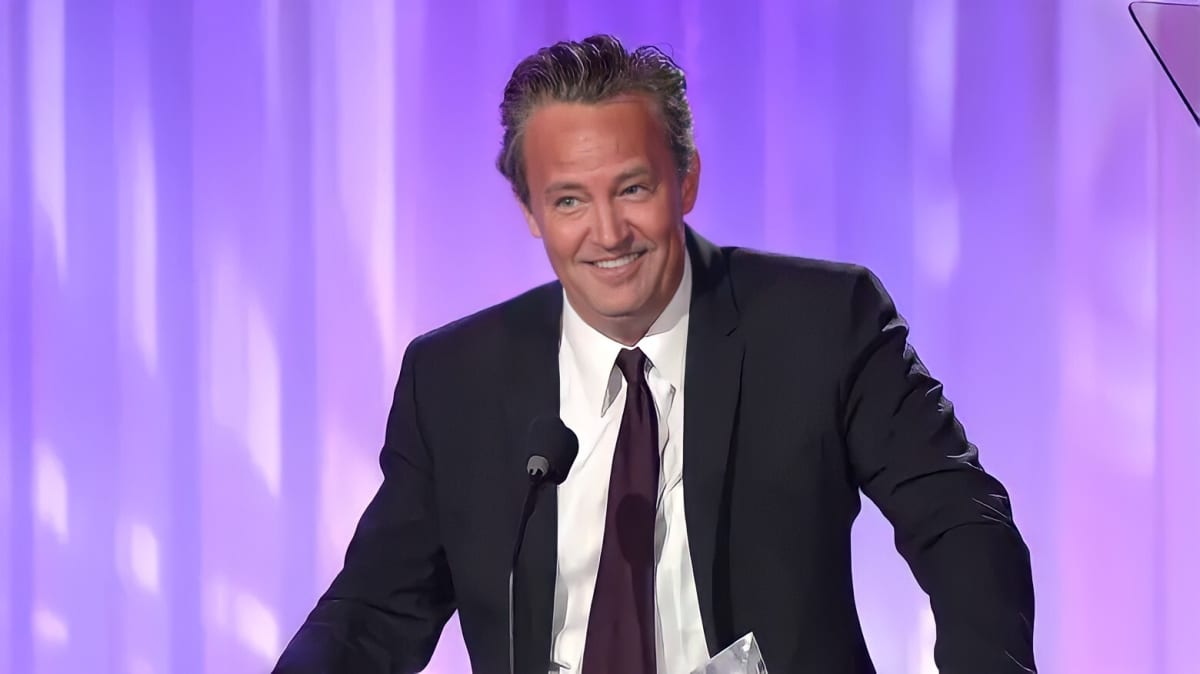 Matthew Perry smiling against a purple background
