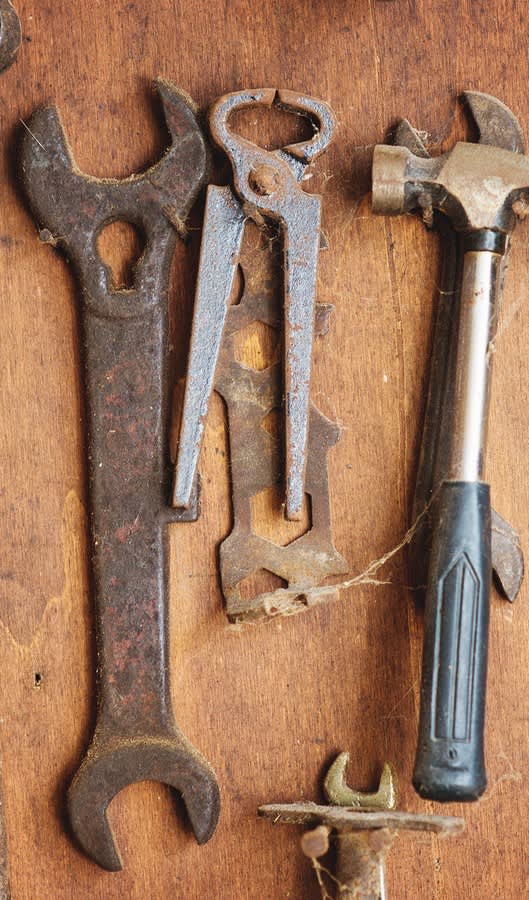 Rusted old wrench and assorted tools on table
