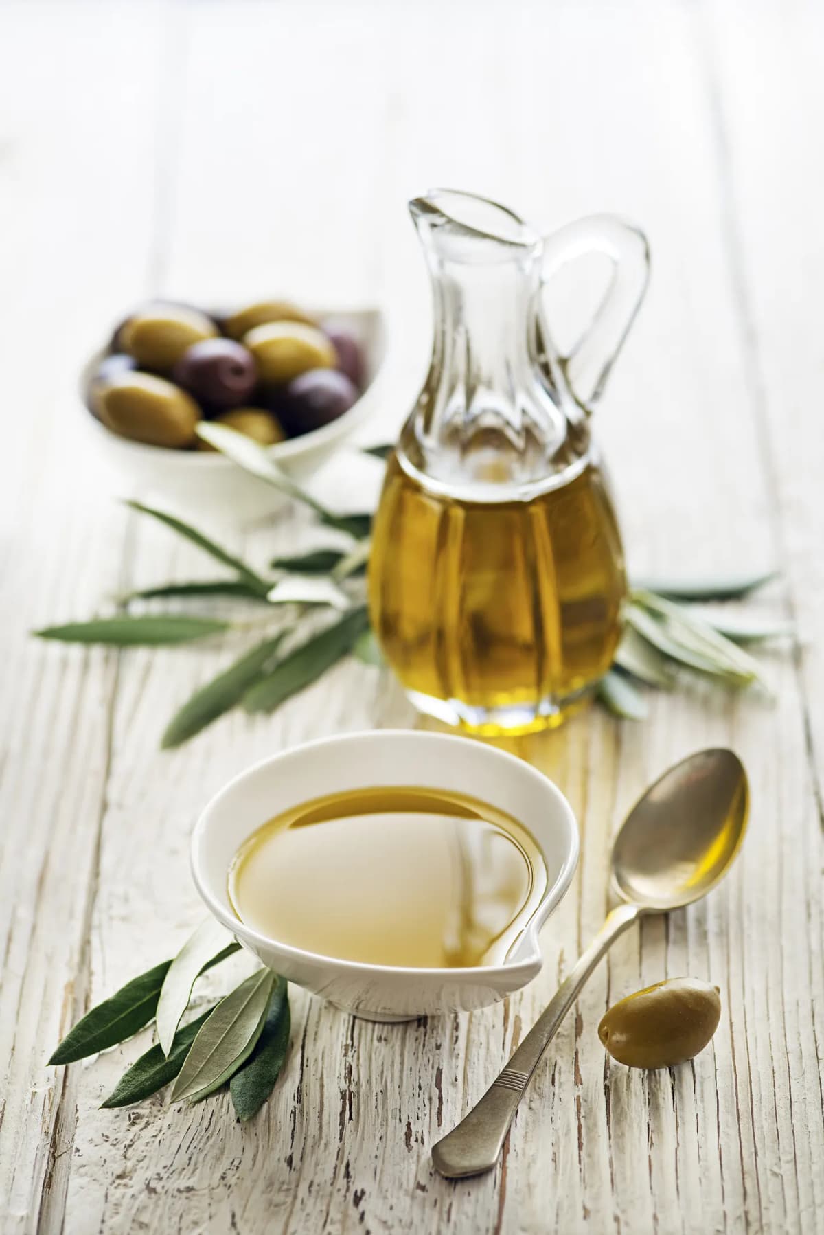 A bowl of olives, olive oil, and a jar of olive oil