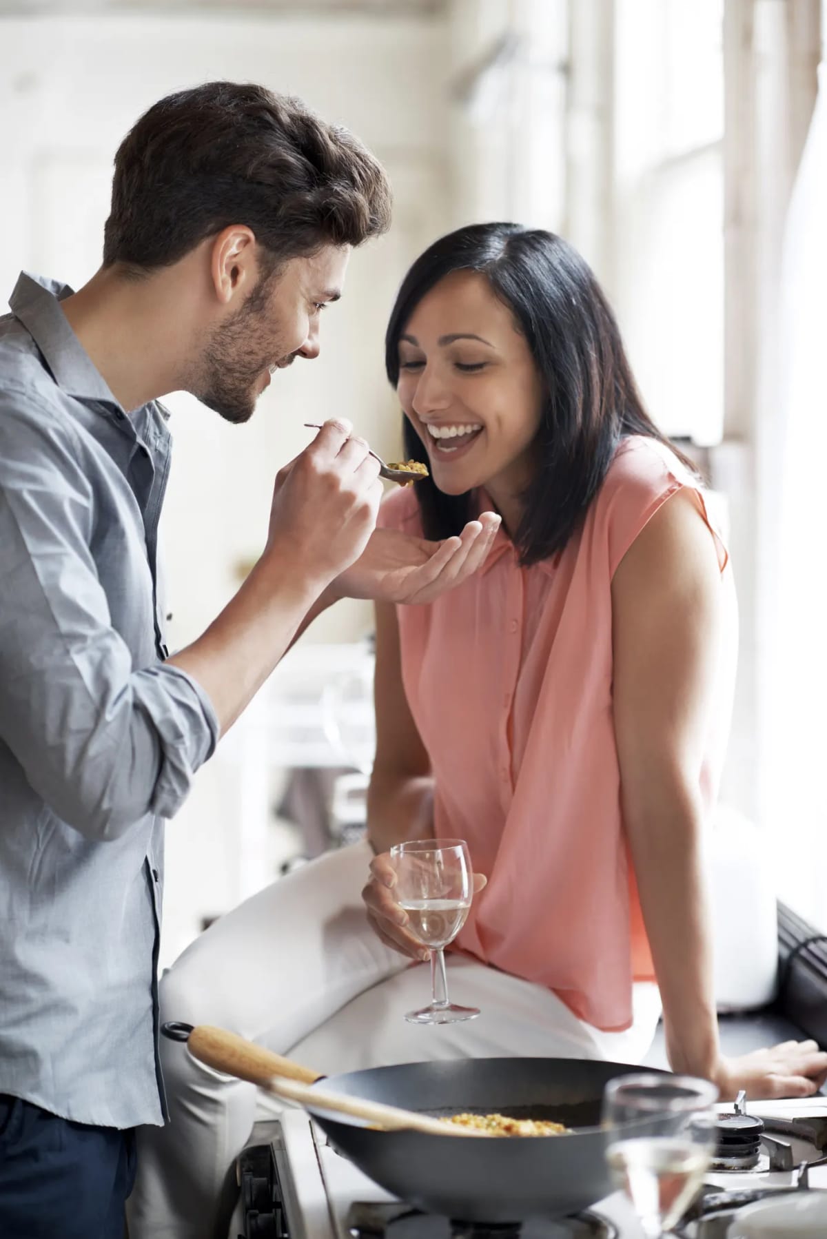 A man feeding a spoonful of food to a smiling woman