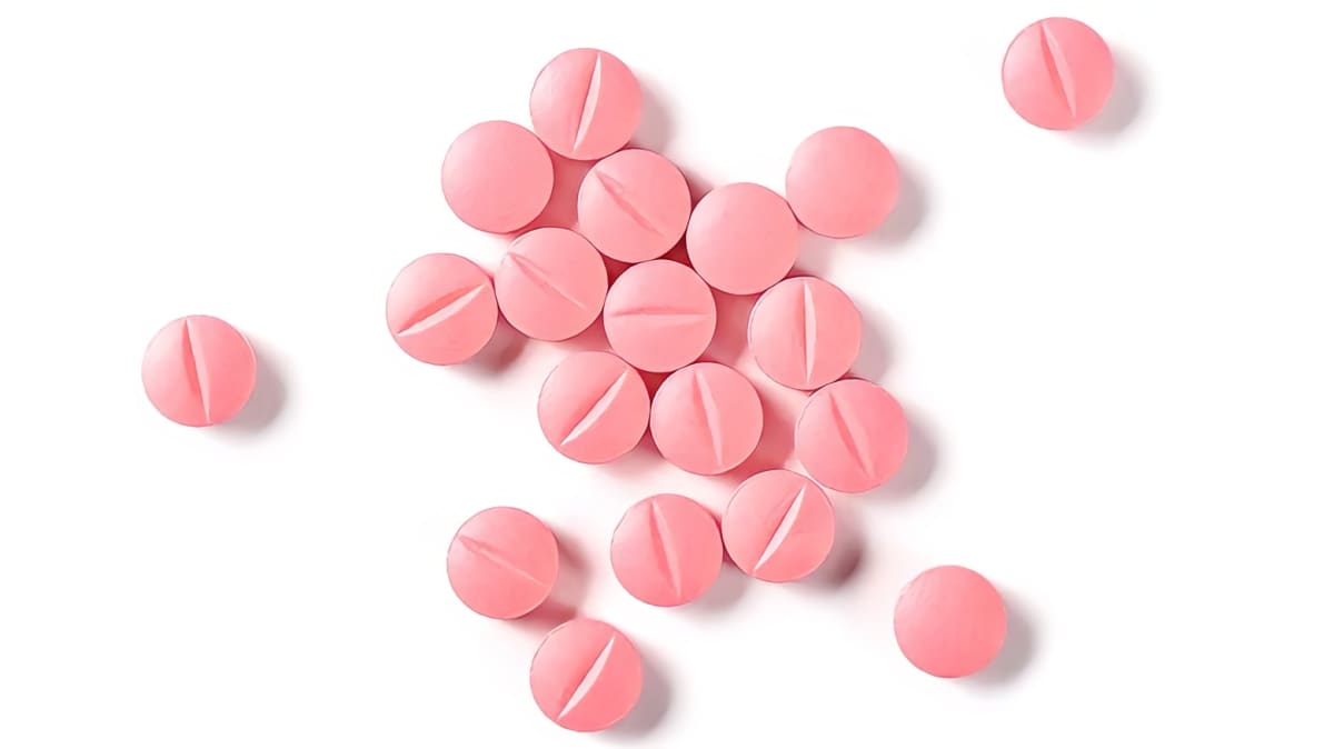 Pink pills against a white background